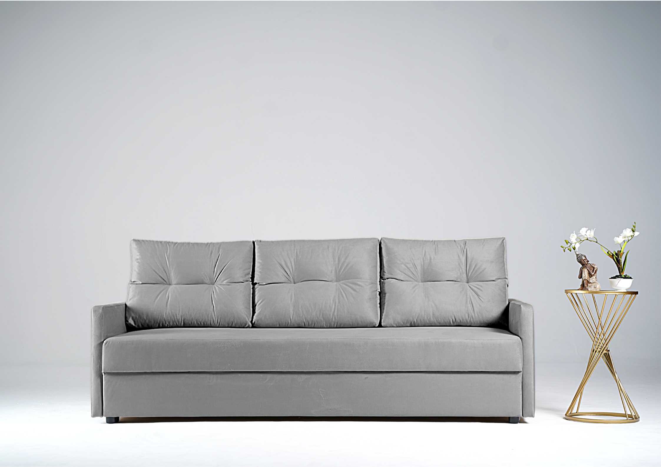 Szara sofa z pikowanymi poduszkami